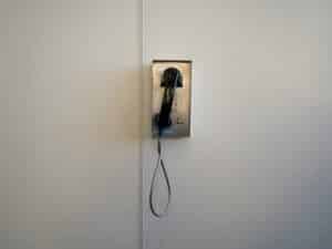 A vintage, wall-mounted payphone in a minimalist setting, showcasing retro technology.