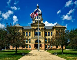 Grand courthouse in Cedar Rapids with an American flag in a bright blue sky.