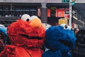 Two vibrant character costumes stand at a busy urban intersection in New York City.