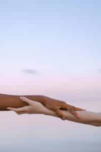 Two hands of different skin tones reaching for each other, symbolizing unity and diversity.