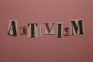 Paper cutouts spelling 'Activism' on a pink surface, emphasizing social movement themes.