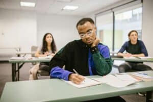 Students in a classroom focusing on their exam papers, depicting diverse educational setting.